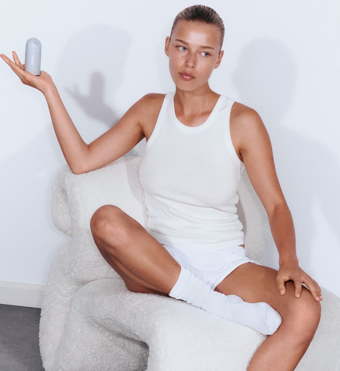 model sitting on a white couch, holding peptide glazing fluid